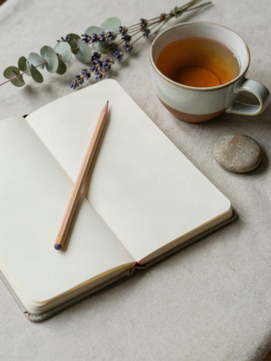Cuaderno abierto, lápiz e infusión sobre lino